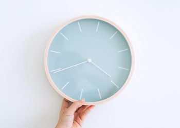 hand holding light blue clock on white background intermittent fasting and weight loss