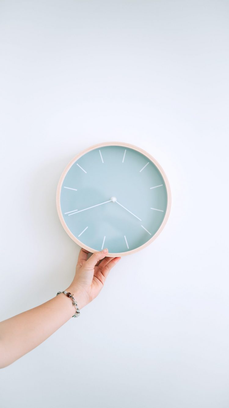 hand holding light blue clock on white background intermittent fasting and weight loss