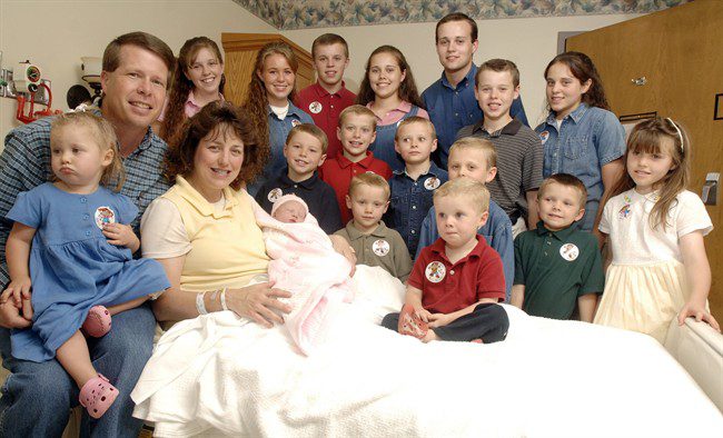 FILE — In this Aug. 2, 2007 file photo, Michelle Duggar, left, poses with her husband Jim Bob, second from left, and children, including their oldest son Josh, tallest standing, after the birth of her 17th child in Rogers, Ark.