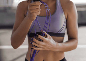 woman in purple workout shirt holding jump rope