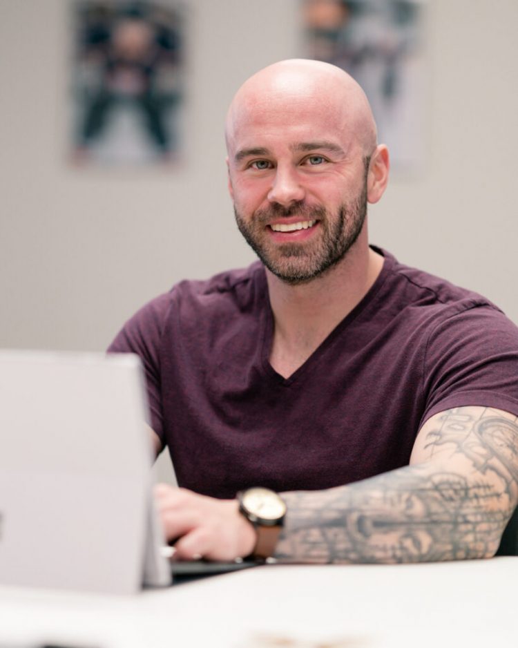 Photograph of nutrition coach Dan Garner sitting at a desk in front of a laptop computer.