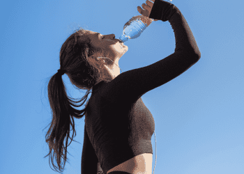 woman drinking water after workout on hot day