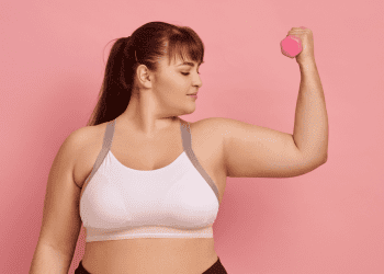 woman lifting weight with pink background