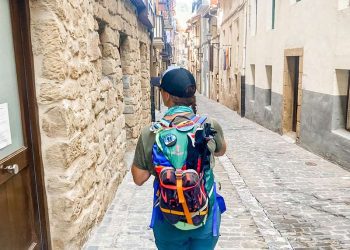 Woman with backpack walking into historic Spanish town