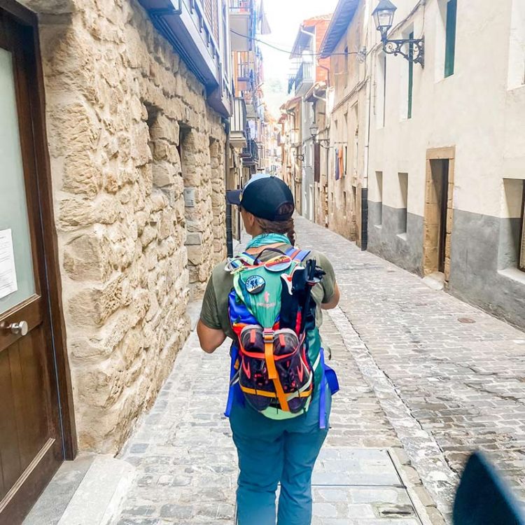 Woman with backpack walking into historic Spanish town