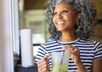 Smiling woman drinking green juice as a part of a healthy morning routine