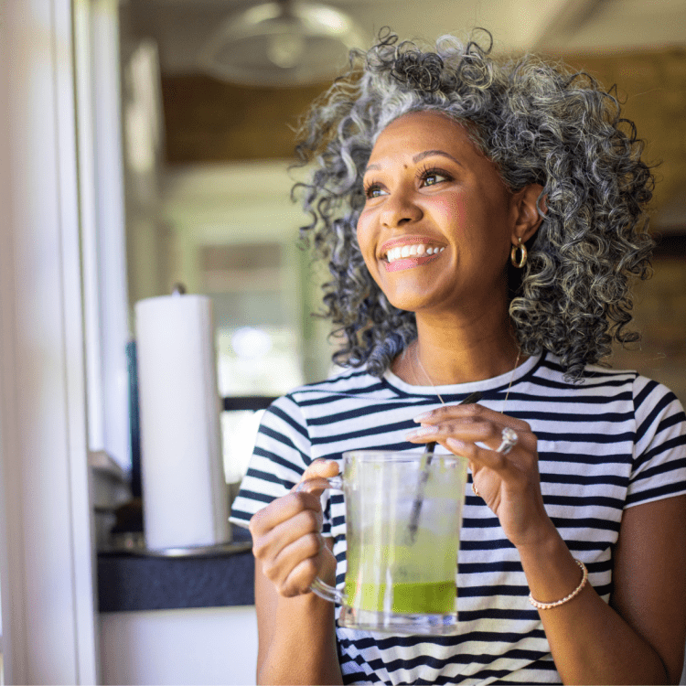 Smiling woman drinking green juice as a part of a healthy morning routine