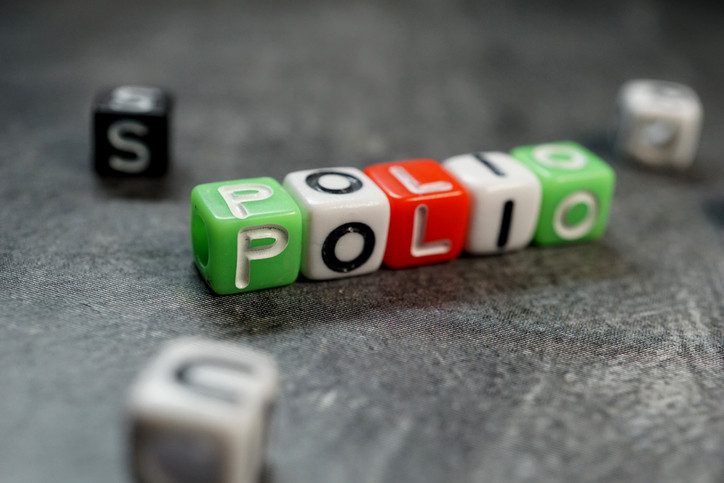 Dice of different colors spelling out "polio" on a dark background
