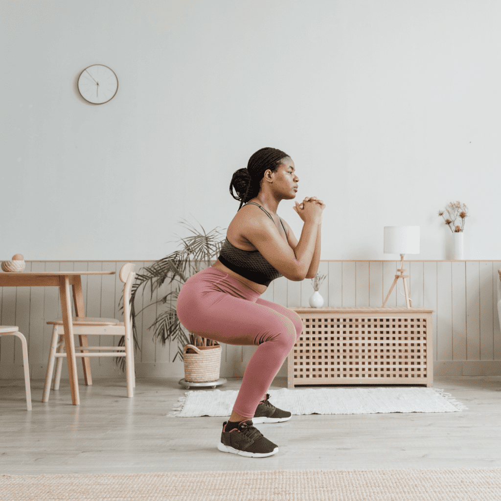 woman in pink legging doing a workout squat in her home