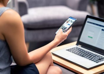 Person checking social media on their phone and laptop