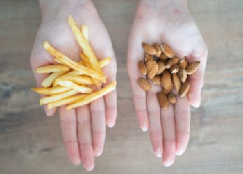Two outstretched hands with french fries in one and almonds in the other