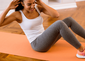 Women performing oblique crunches on orange yoga mat