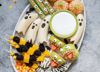 A large plate of healthy halloween recipes like banana ghosts, pumpkin clementines, celery fingers and apple monsters