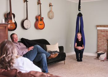 Ayden chats with his parents while sitting in a therapy swing in their home in Ohio. The swing helps Ayden manage some of his pain, allowing him to rest and recharge when he is tired or in pain. (Julie Renée Jones for TIME)