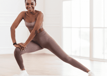 Young woman performing a lateral lunge on yoga mat with workout clothes