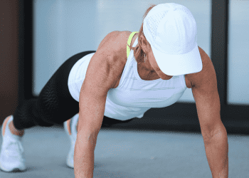 Chris Freytag doing a push up with white hat, white tank and black leggings