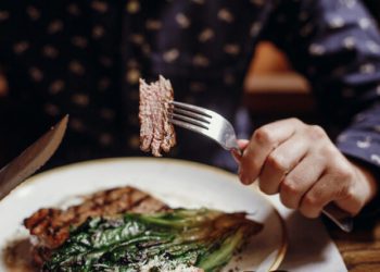 Man holding fork and knife while eating steak