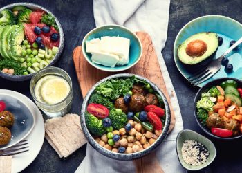 A table spread with bowls full of vegetables, fruits, beans, and other proteins; healthy food choices