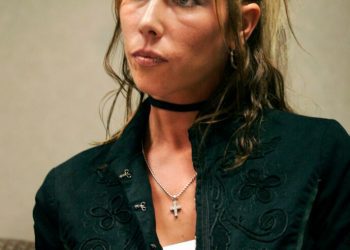 Kimberly Anne Scott appearing in dark green jacket and black choker necklace