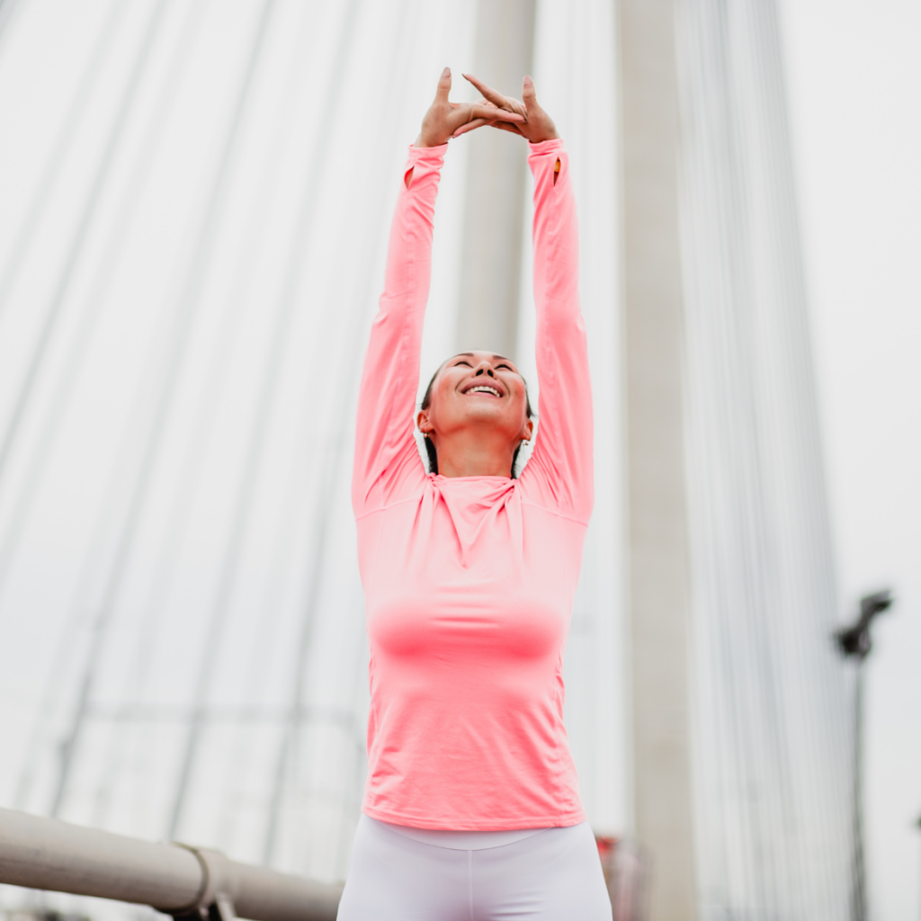 woman stretching to the sky on a bridge