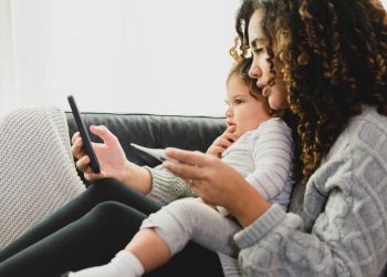 Woman holding baby and thermometer on video call with doctor