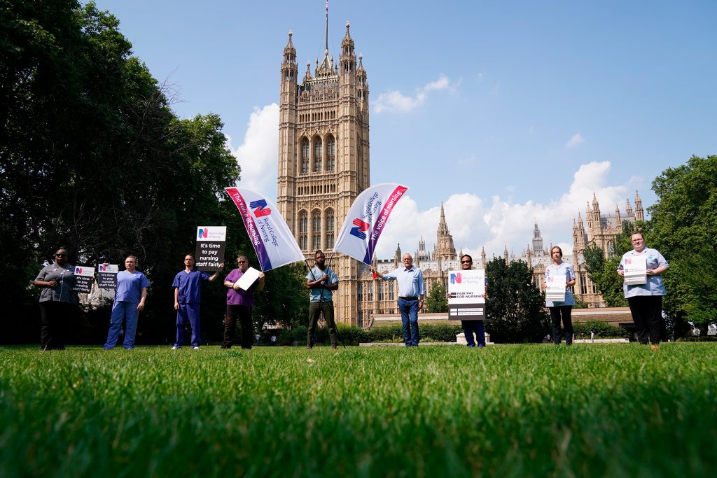 Nurses with placards outside the Royal College of Nursing in Victoria Tower Gardens, London, following the government's announcement of the NHS pay offer, on July 21, 2021. (Jonathan Brady—PA Wire/AP)